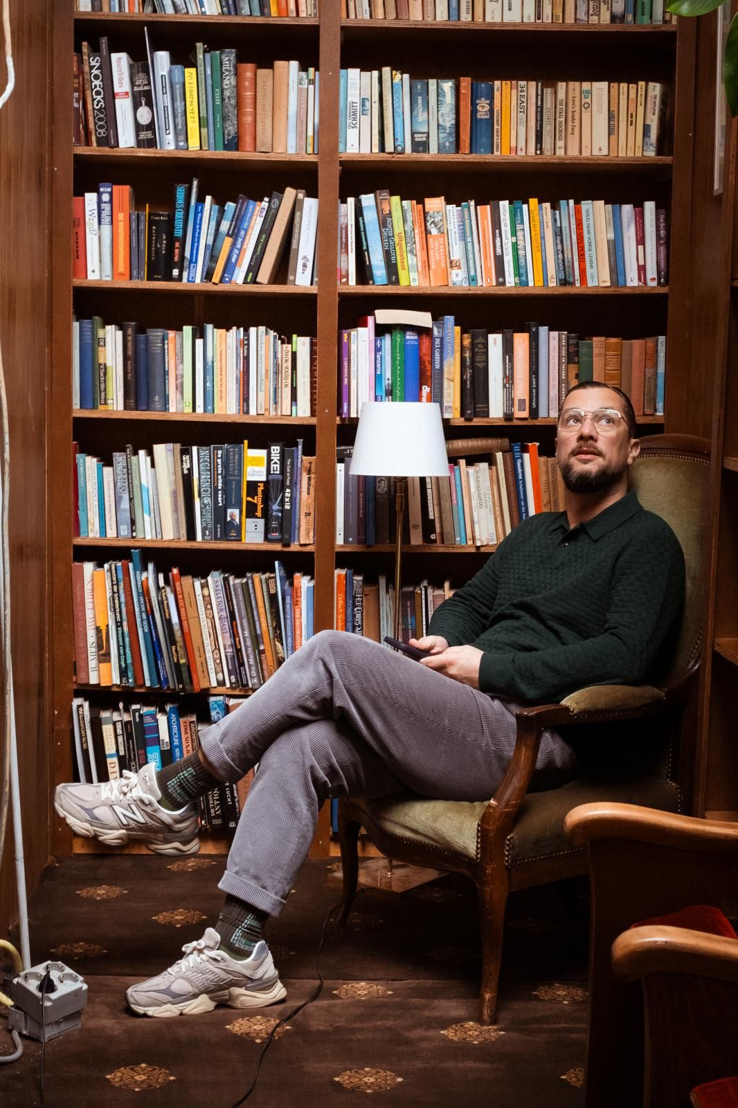 Paul Baptista in a leather armchair in front of a wall of books.